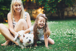 stock-photo-mom-with-her-child-relaxing-with-english-highland-white-terrier-dog-on-grass